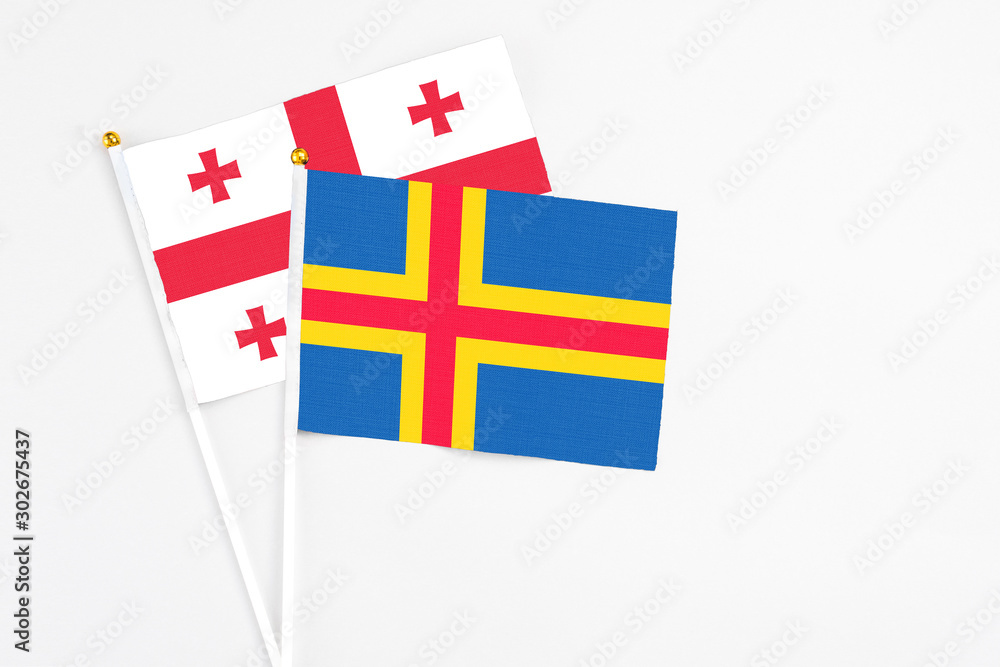 Aland Islands and Georgia stick flags on white background. High quality fabric, miniature national flag. Peaceful global concept.White floor for copy space.