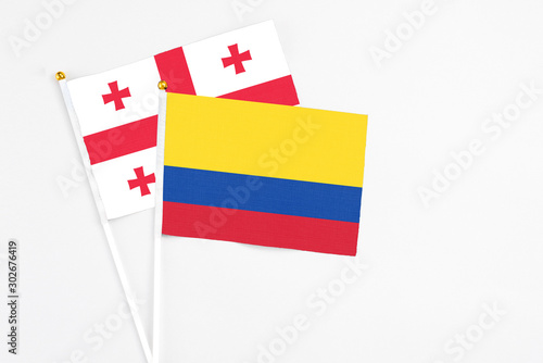 Colombia and Georgia stick flags on white background. High quality fabric  miniature national flag. Peaceful global concept.White floor for copy space.