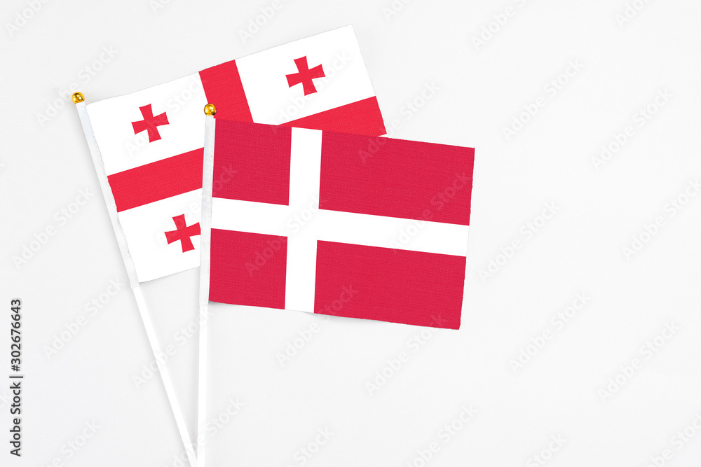 Denmark and Georgia stick flags on white background. High quality fabric, miniature national flag. Peaceful global concept.White floor for copy space.