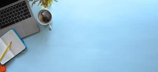 Simple Top view table - Creative flat lay office desk. Laptop, notebooks and coffee cup on blue background. Panorama banner background with copy space.