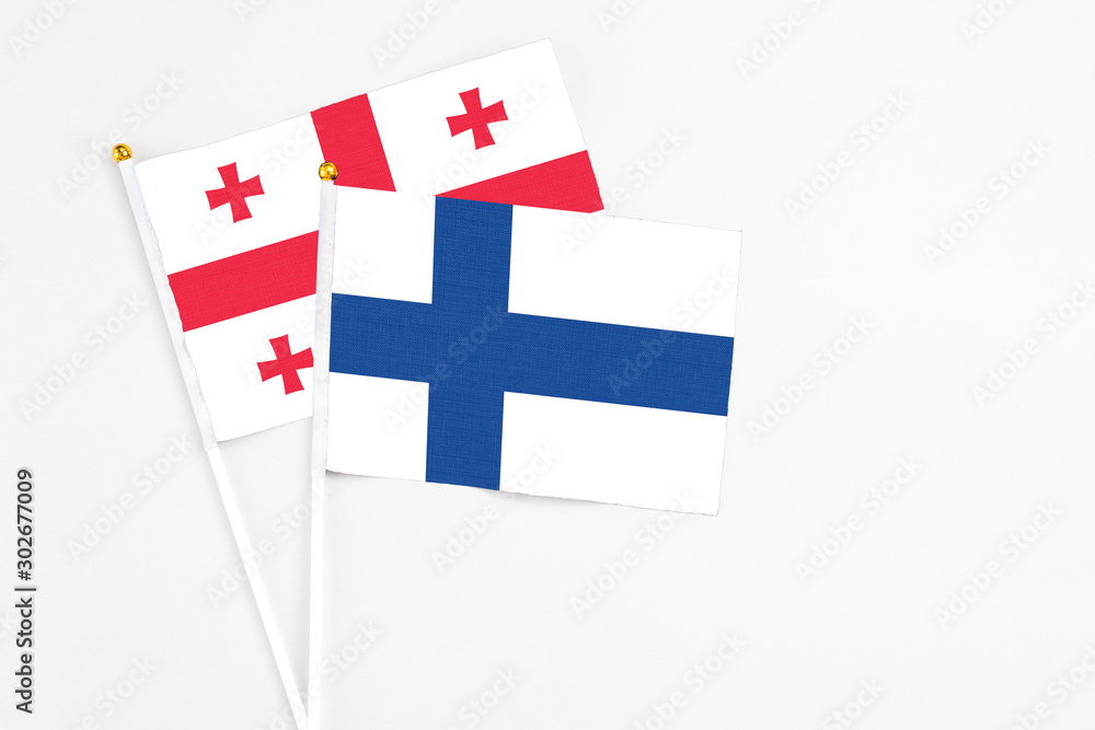 Finland and Georgia stick flags on white background. High quality fabric, miniature national flag. Peaceful global concept.White floor for copy space.