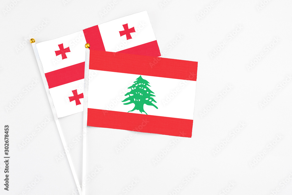 Lebanon and Georgia stick flags on white background. High quality fabric, miniature national flag. Peaceful global concept.White floor for copy space.