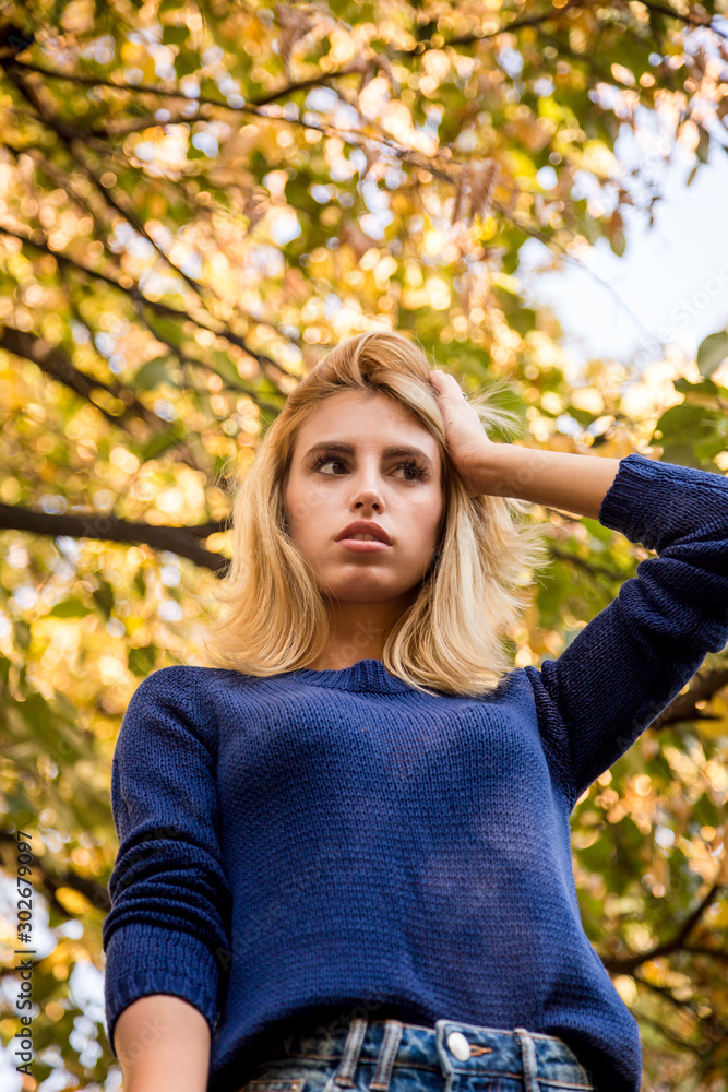 autumn season. portrait of a woman with blue sweater playing with leaves autumn season. portrait of a woman with blue sweater playing with leaves