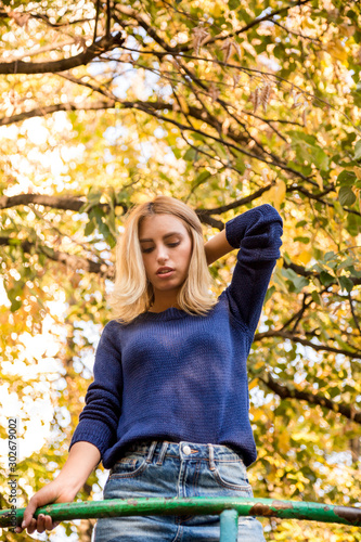 autumn season. portrait of a woman with blue sweater playing with leaves