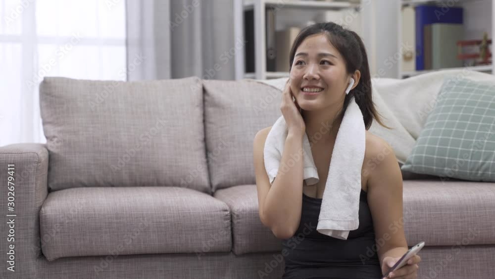 Beautiful young asian korean woman in sports clothing using smart phone and earphones smiling while listening to favorite song. healthy lifestyle girl with towel around neck enjoy music on cellphone Beautiful young asian korean woman in sports clothing using smart phone and earphones smiling while listening to favorite song. healthy lifestyle girl with towel around neck enjoy music on cellphone