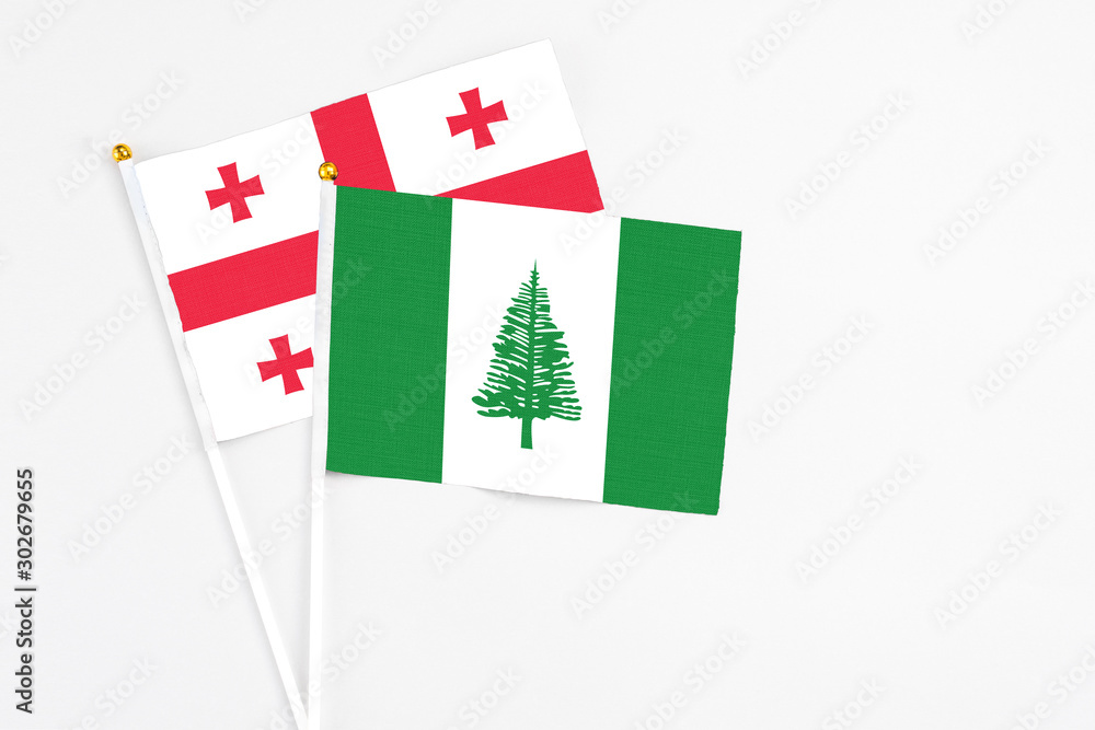 Norfolk Island and Georgia stick flags on white background. High quality fabric, miniature national flag. Peaceful global concept.White floor for copy space.