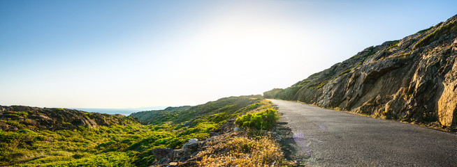 Empty long mountain road to the horizon on a sunny summer day at bright sunset