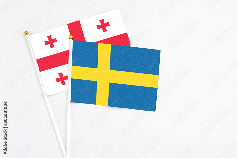 Sweden and Georgia stick flags on white background. High quality fabric, miniature national flag. Peaceful global concept.White floor for copy space.