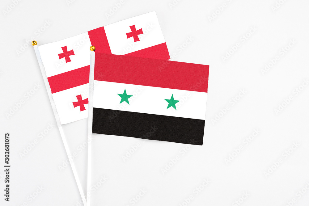 Syria and Georgia stick flags on white background. High quality fabric, miniature national flag. Peaceful global concept.White floor for copy space.