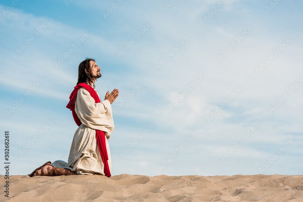 man praying on knees in desert on golden sand man praying on knees in desert on golden sand