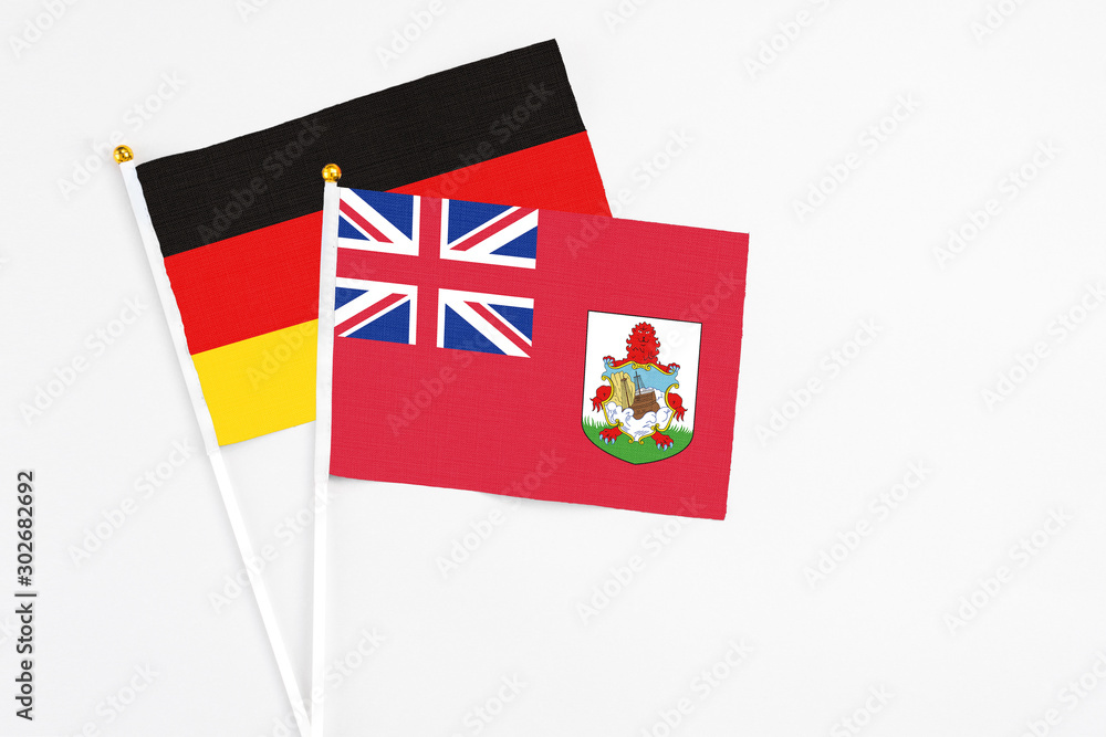 Fototapeta premium Bermuda and Germany stick flags on white background. High quality fabric, miniature national flag. Peaceful global concept.White floor for copy space.