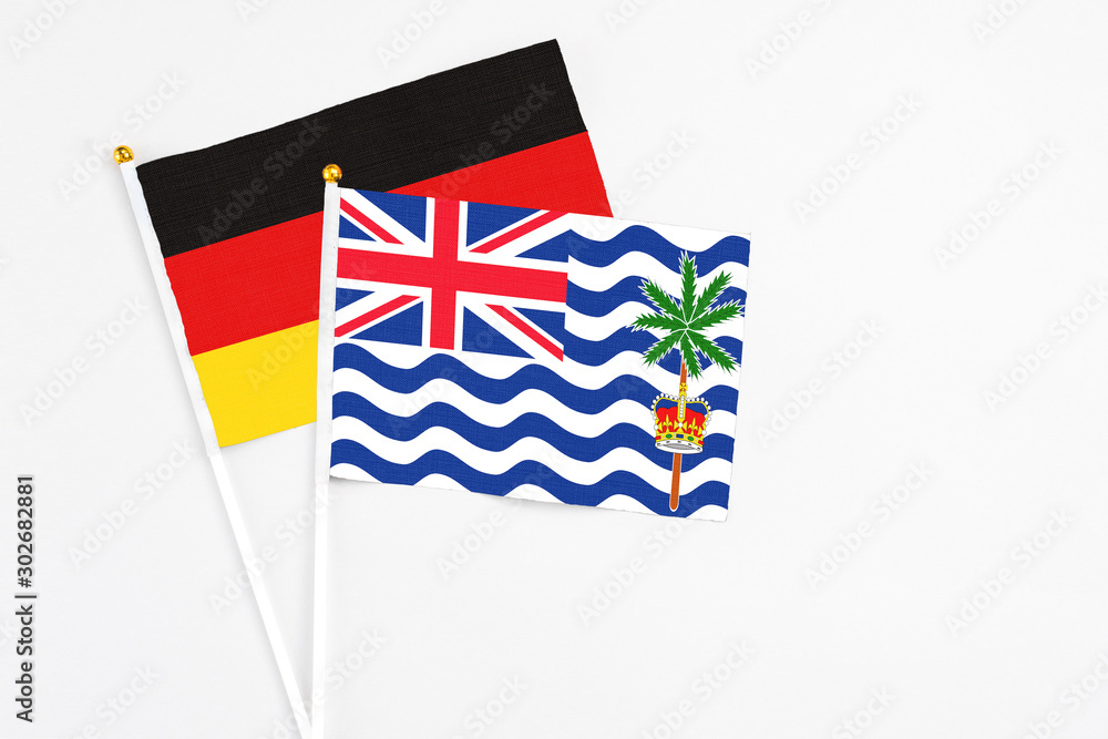 Fototapeta premium British Indian Ocean Territory and Germany stick flags on white background. High quality fabric, miniature national flag. Peaceful global concept.White floor for copy space.