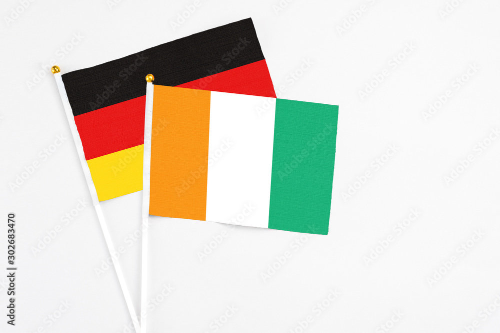 Cote D'Ivoire and Germany stick flags on white background. High quality fabric, miniature national flag. Peaceful global concept.White floor for copy space. Cote D'Ivoire and Germany stick flags on white background. High quality fabric, miniature national flag. Peaceful global concept.White floor for copy space.