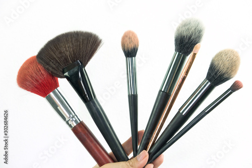 Professional make-up brush cosmetic in female hand beautician isolated on white background