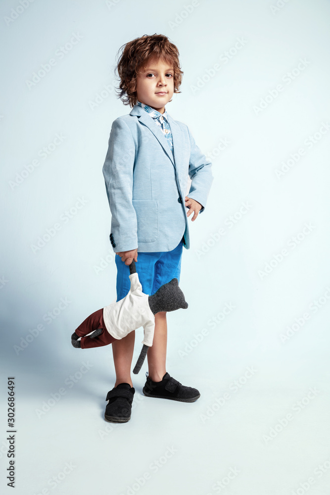 Pretty young boy in casual clothes on white studio background. Fashionable posing. Caucasian male preschooler with bright facial emotions. Childhood, having fun. Posing with his teddy bear. Stylish. Pretty young boy in casual clothes on white studio background. Fashionable posing. Caucasian male preschooler with bright facial emotions. Childhood, having fun. Posing with his teddy bear. Stylish.