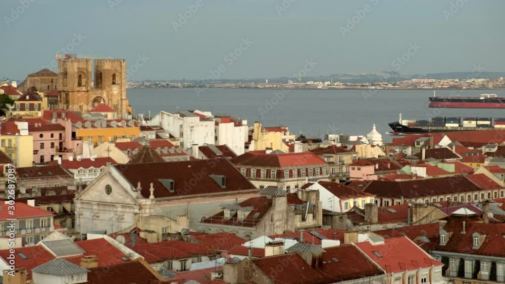 Large cargo ship passes behind the rooftops of central Lisbon at sunset. Large cargo ship passes behind the rooftops of central Lisbon at sunset.
