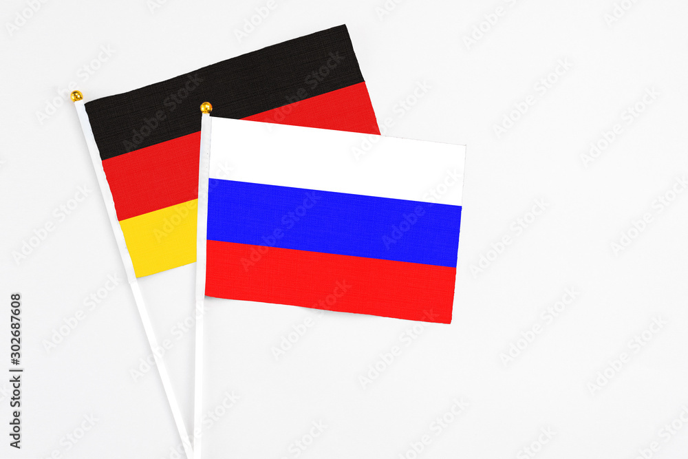 Russia and Germany stick flags on white background. High quality fabric, miniature national flag. Peaceful global concept.White floor for copy space. Russia and Germany stick flags on white background. High quality fabric, miniature national flag. Peaceful global concept.White floor for copy space.
