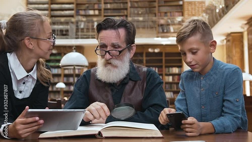 Respected 70-aged bearded man dissappointing because 12s grandchildren playing on modern devices rather then read exciting book photo