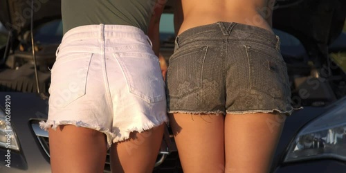 two beautiful and sexy butt, ass in shorts on the background of the car photo