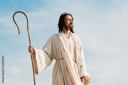bearded man holding wooden cane against blue sky and clouds © LIGHTFIELD STUDIOS