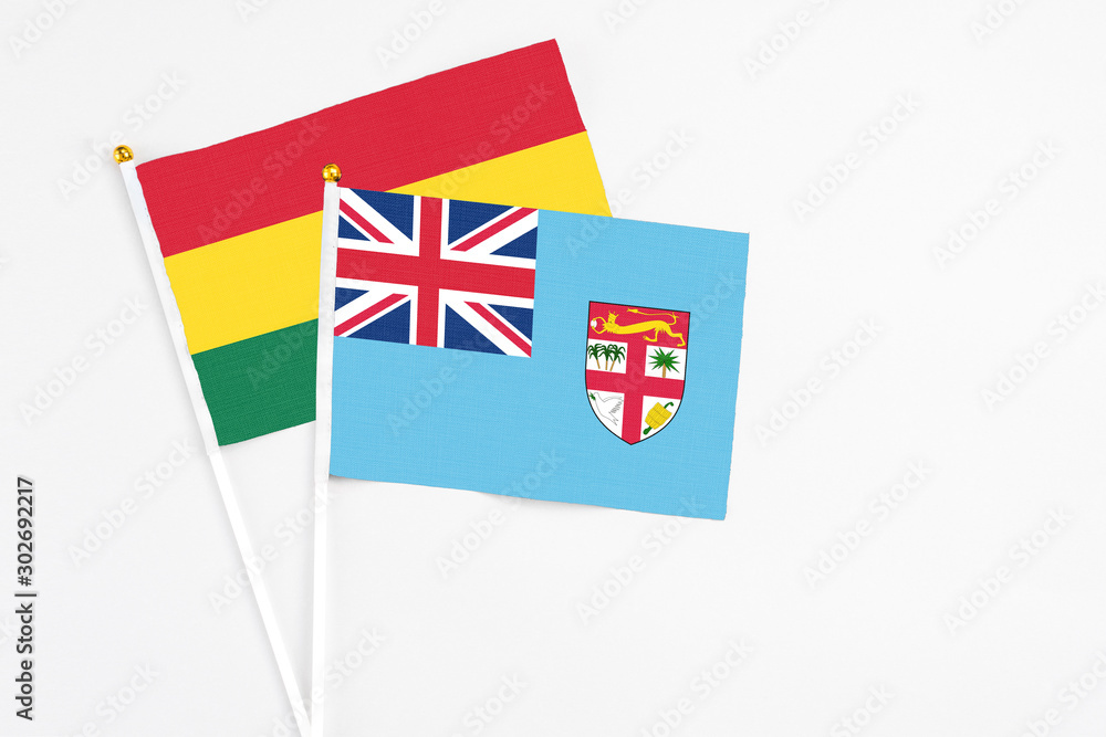 Fototapeta premium Fiji and Ghana stick flags on white background. High quality fabric, miniature national flag. Peaceful global concept.White floor for copy space.