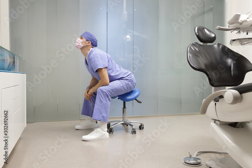 Dentist stretching body. Caucasian man exercising on dental mobile saddle in his office.