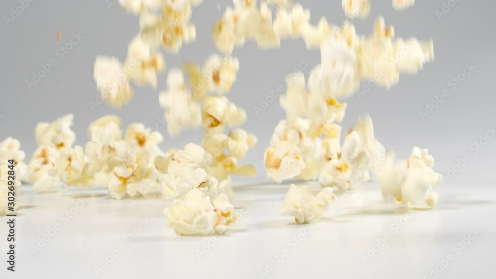 Fresh popcorn falling onto a white surface in slow motion Fresh popcorn falling onto a white surface in slow motion