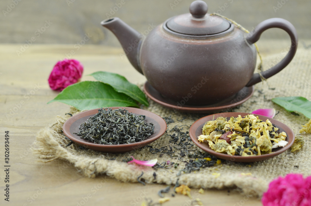 Dry tea in brown plate and teapot on wooden table Dry tea in brown plate and teapot on wooden table