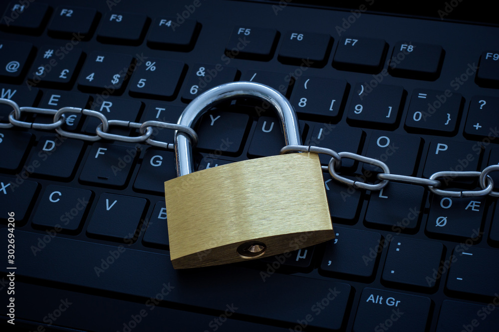 Computer keyboard protected by a metal chain and lock. Concept photo of cybercrime and internet and computer security and safety. Computer keyboard protected by a metal chain and lock. Concept photo of cybercrime and internet and computer security and safety.
