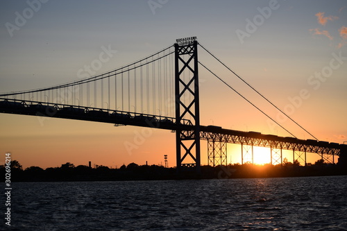 Ambassador Bridge between Detroit, Michigan and Windsor, Ontario. Sunset on the Detroit River with the silhouette of the bridge. Border crossing between the US and Canada © Julie