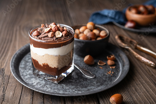 Layered dessert with chocolate mousse, cream cheese and whipped cream mixed with chestnut puree, topped with hazelnuts in a glass jar photo