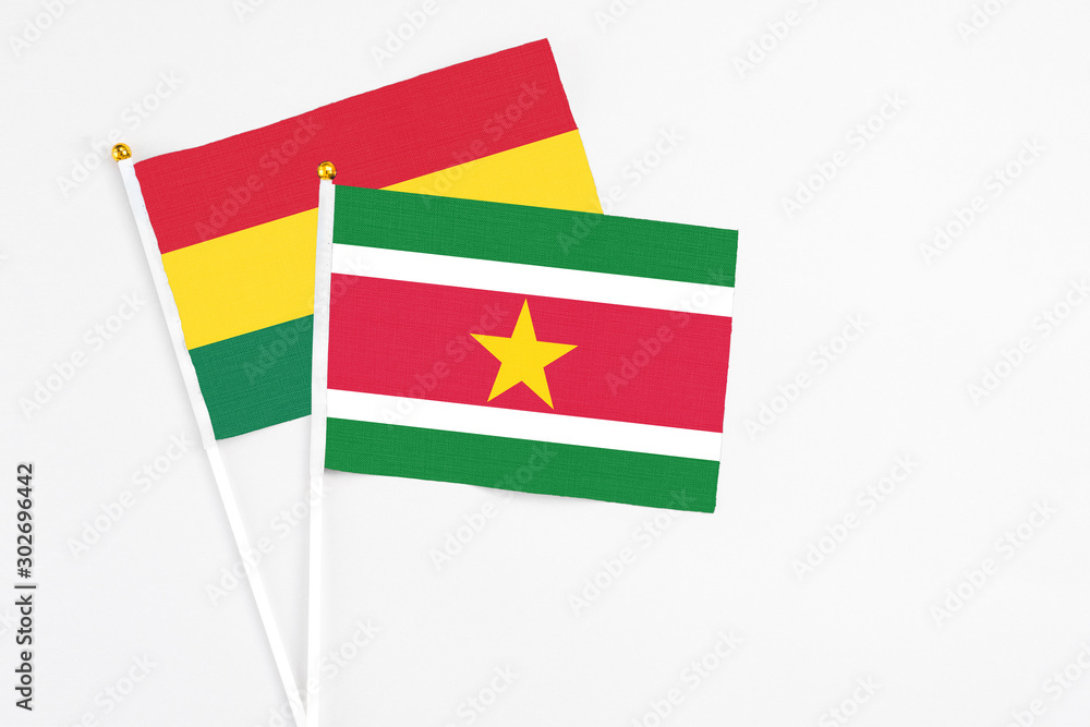 Suriname and Ghana stick flags on white background. High quality fabric, miniature national flag. Peaceful global concept.White floor for copy space.