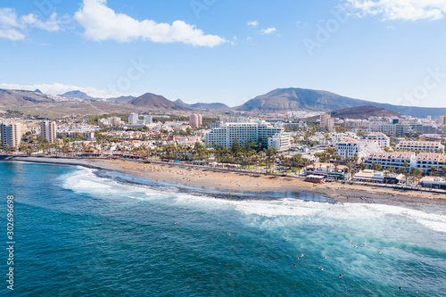 Aerial drone view of Playa de las Americas area, Tenerife, Spain. Amazing ocean landscape with lots of hotels and restaurants. Surfers have lessons in the water. photo