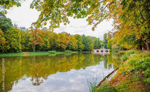 Fototapeta Naklejka Na Ścianę i Meble -  Bridge in the park on the lake. Royal Palace on the Water in Lazienki Park, Warsaw. Lake view in autumn