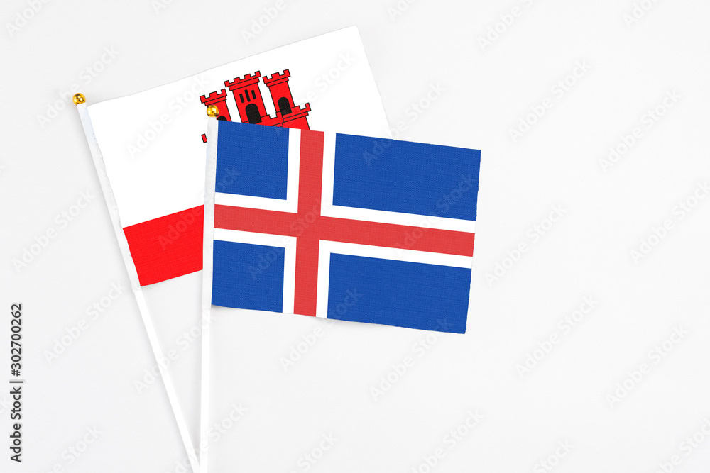 Iceland and Gibraltar stick flags on white background. High quality fabric, miniature national flag. Peaceful global concept.White floor for copy space.