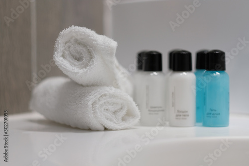Mini bottles with cosmetic products and towels on table, space for text. Hotel amenities