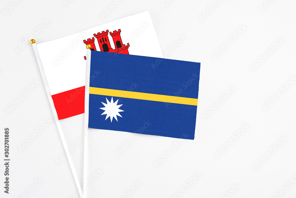 Nauru and Gibraltar stick flags on white background. High quality fabric, miniature national flag. Peaceful global concept.White floor for copy space. Nauru and Gibraltar stick flags on white background. High quality fabric, miniature national flag. Peaceful global concept.White floor for copy space.