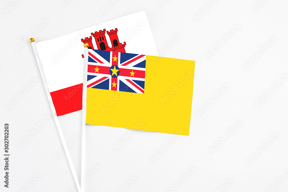 Niue and Gibraltar stick flags on white background. High quality fabric, miniature national flag. Peaceful global concept.White floor for copy space. Niue and Gibraltar stick flags on white background. High quality fabric, miniature national flag. Peaceful global concept.White floor for copy space.