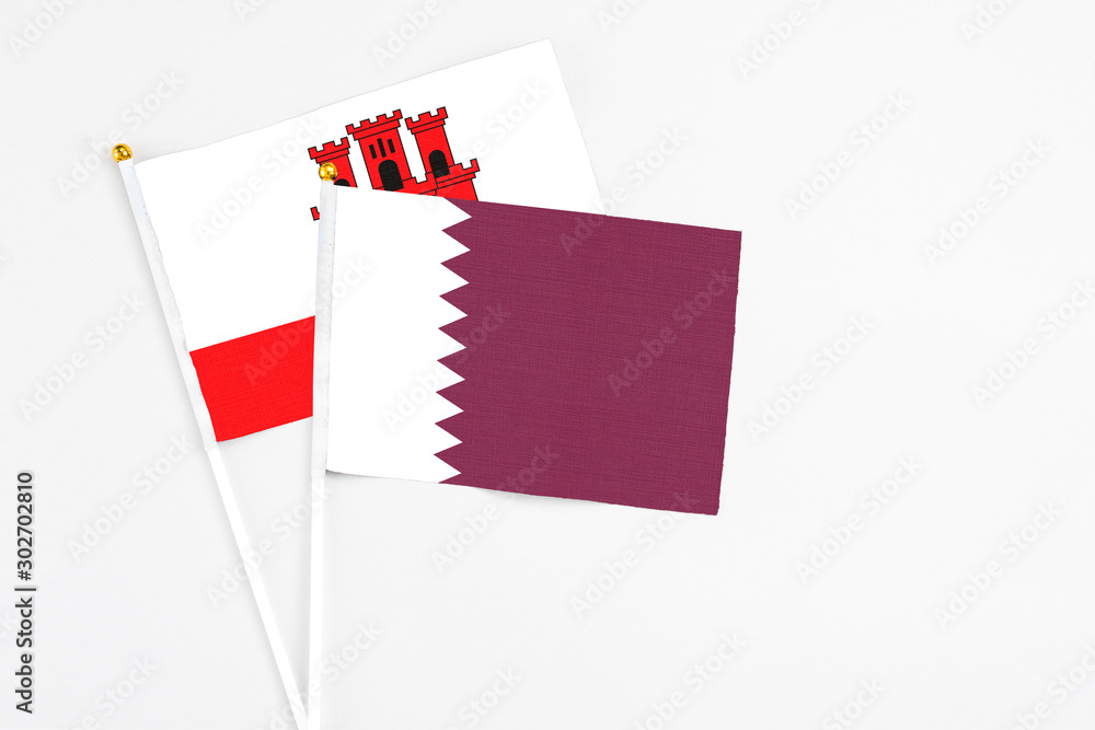 Qatar and Gibraltar stick flags on white background. High quality fabric, miniature national flag. Peaceful global concept.White floor for copy space.