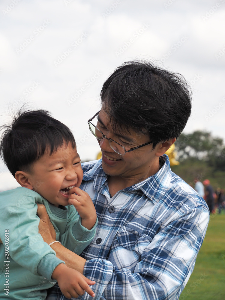 Asian child boy and father laughing together outdoor park. Dad and cute son in happy moment with smiling face in happy family time father's day. Asian child boy and father laughing together outdoor park. Dad and cute son in happy moment with smiling face in happy family time father's day.
