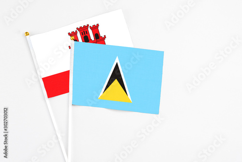 Saint Lucia and Gibraltar stick flags on white background. High quality fabric  miniature national flag. Peaceful global concept.White floor for copy space.