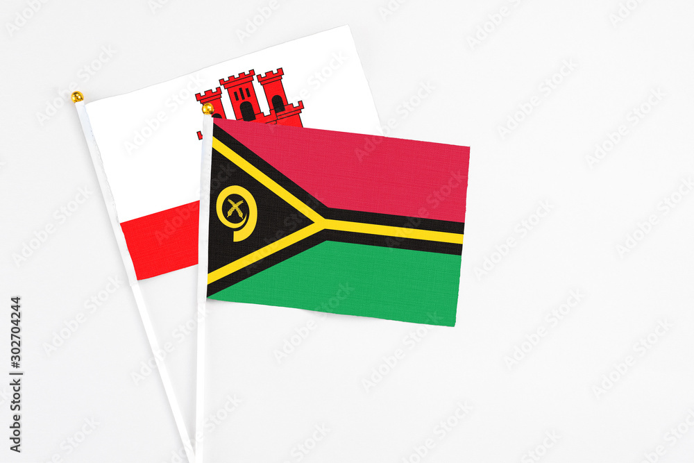 Vanuatu and Gibraltar stick flags on white background. High quality fabric, miniature national flag. Peaceful global concept.White floor for copy space.
