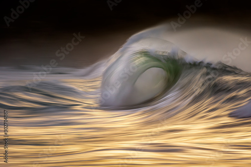 Photo of a big wave breaking at sunset with in camera panning technique