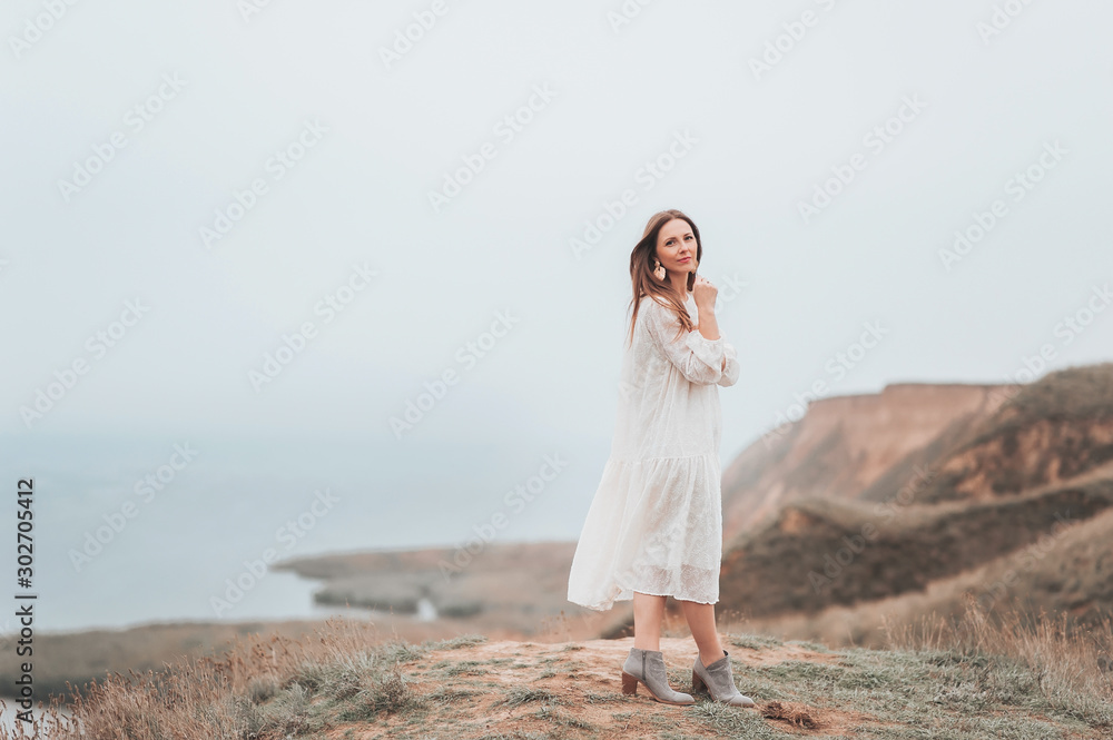 Dreamy woman in white dress standing achieving the top of mountain and enjoy windy. Successful woman relaxing life. Inspiration loneliness harmony concept. Woman energy and destination. Dreamy woman in white dress standing achieving the top of mountain and enjoy windy. Successful woman relaxing life. Inspiration loneliness harmony concept. Woman energy and destination.