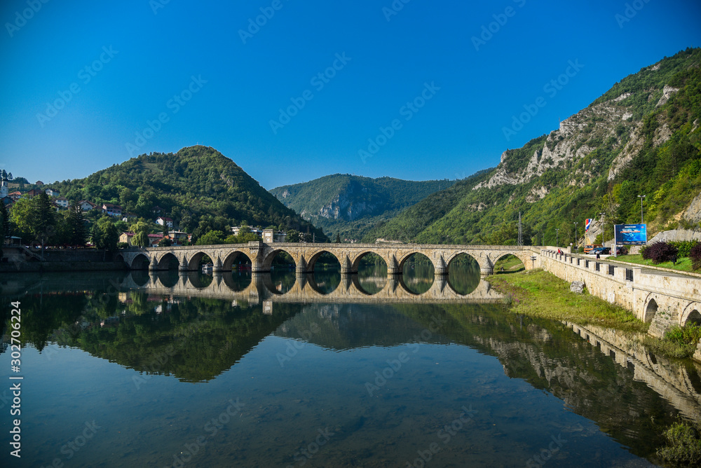 The Ottoman Mehmed Pasa Sokolovic Bridge in Visegrad, Bosnian mountains, with fantastic sky scape and river reflection. Bosnia and Herzegovina.