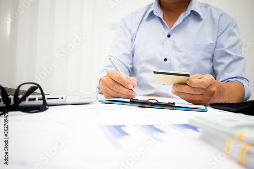 A businessman using cedit crad and holding money for calculate tax in office. photo