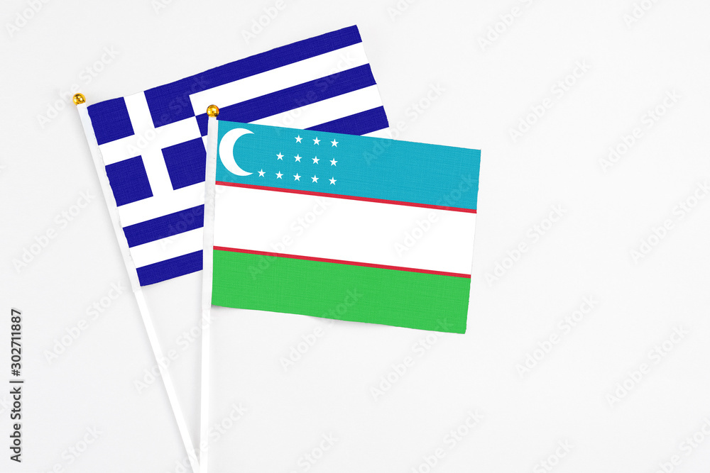 Obraz premium Uzbekistan and Greece stick flags on white background. High quality fabric, miniature national flag. Peaceful global concept.White floor for copy space.