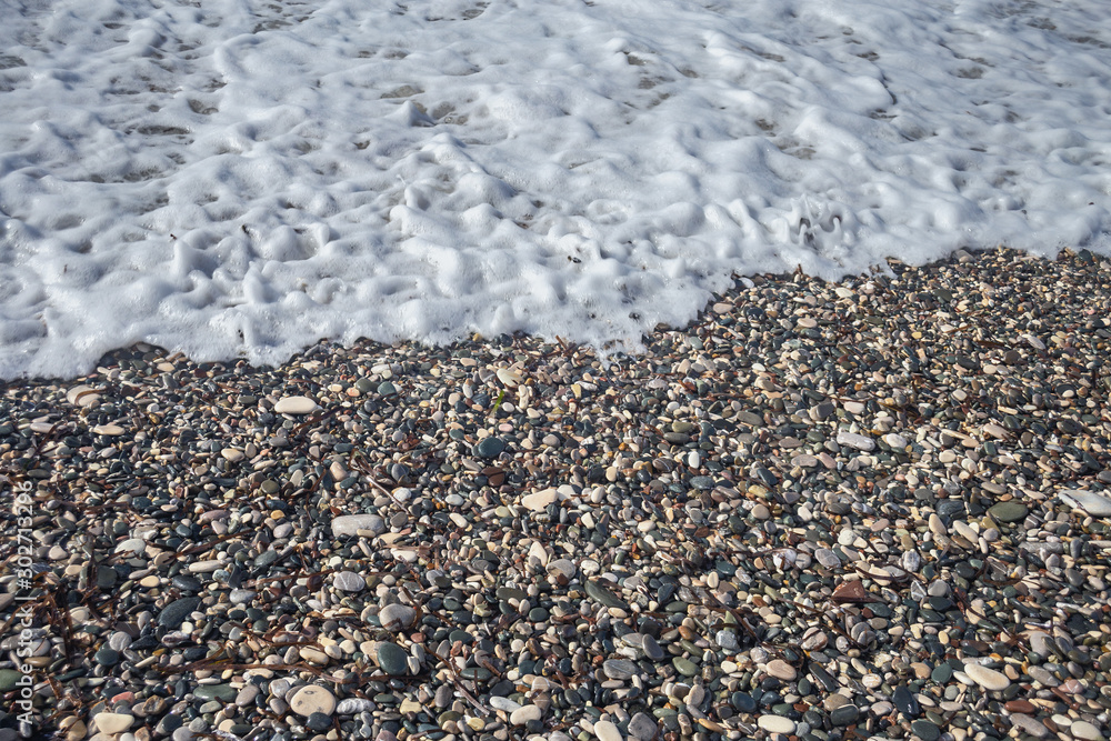 fragment of the pebble beach of Aphrodite in Cyprus with an oncoming foamy sea wave fragment of the pebble beach of Aphrodite in Cyprus with an oncoming foamy sea wave