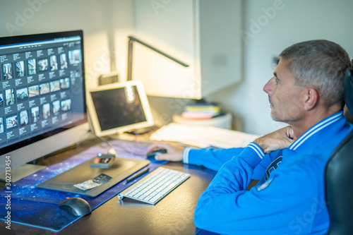 Man working at home computer in front of big screen
