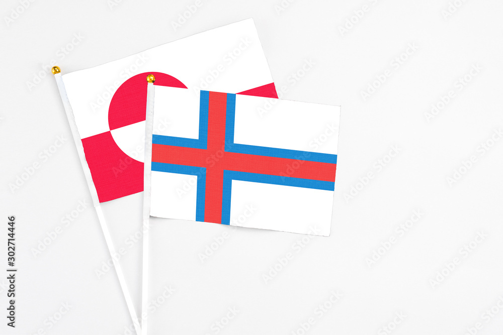 Faroe Islands and Greenland stick flags on white background. High quality fabric, miniature national flag. Peaceful global concept.White floor for copy space.